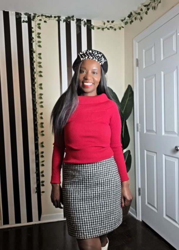 Woman wearing a red sweater with a houndstooth skirt, ivory boots, and a black pearl beret for a Valentine’s Day outfit